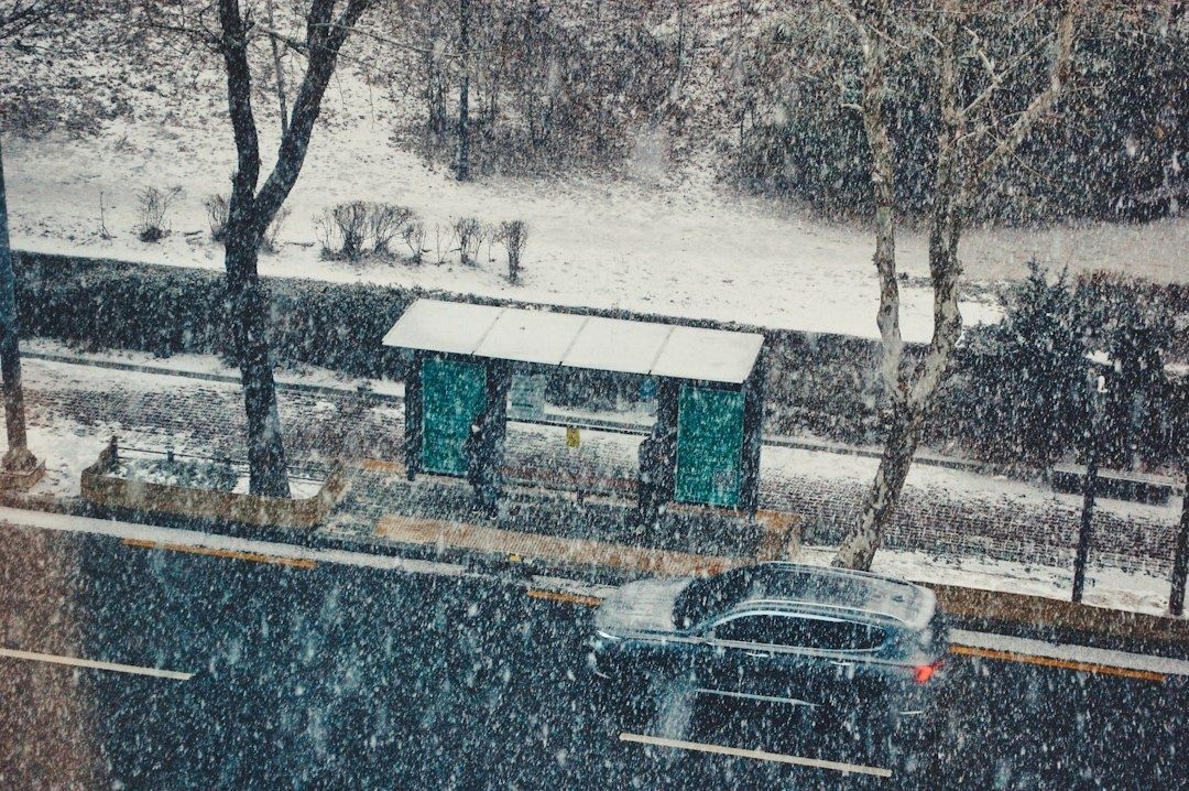 Lumipyryssä oleva bussipysäkki ja tiellä ajava auto